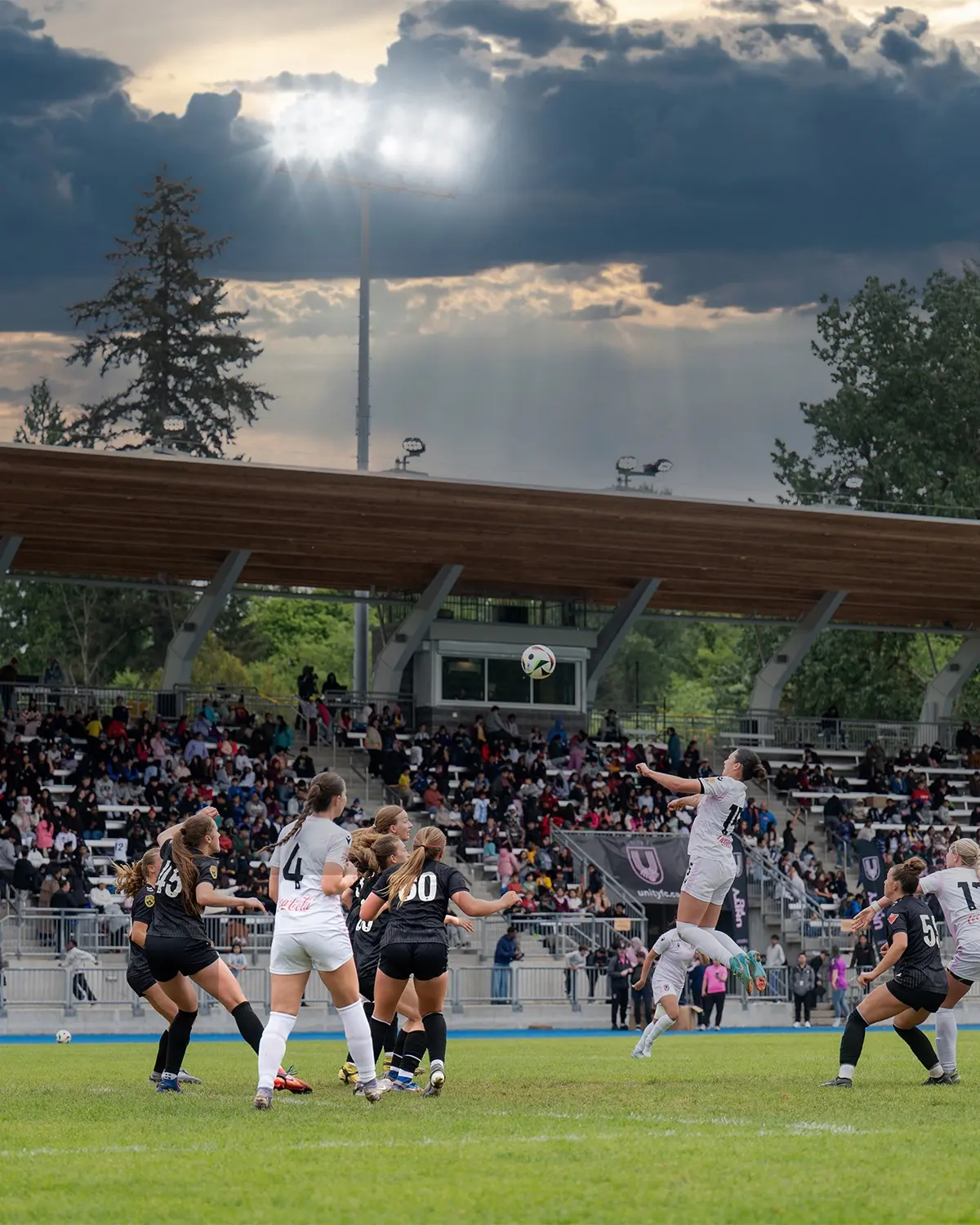 Soccer player rising above a crowded penalty area beneath dramatic stadium lights